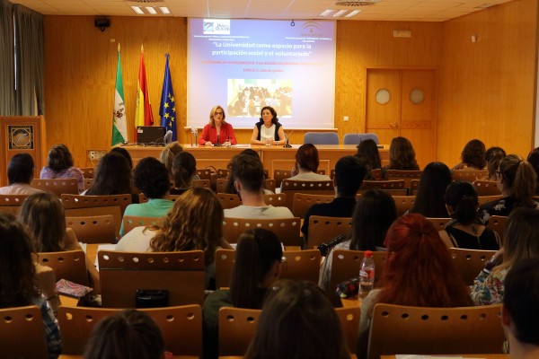 En la mesa, de izquierda a derecha, Rocío Cárdenas Rodríguez, directora general de Programación Social y Cultural de la UPO, e Inmaculada Sancho Porras, responsable de la Oficina de Voluntariado y Solidaridad de esta universidad.