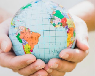 ilustración: globo terráqueo sostenido por dos manos