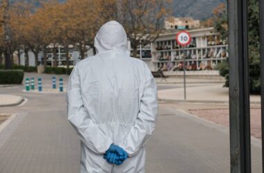 Hombre de espaldas con un equipo de protección individual contempla tumbas en un cementerio