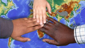 Manos de jóvenes inmigrantes de distinta procedencia sobre un mapa