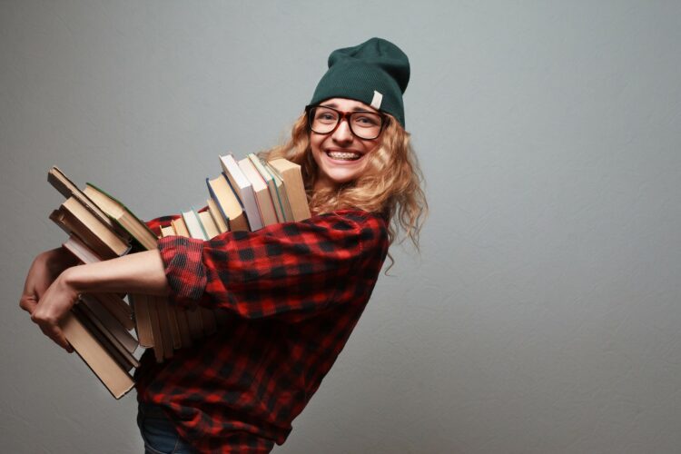 joven sonriente con muchos libros