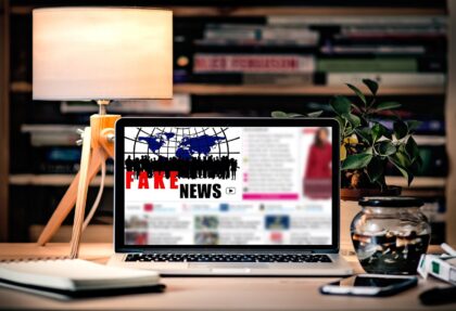 Pantalla de un portátil sobre un escritorio con el texto 'Fake News'