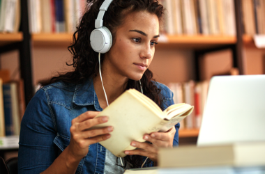 Estudiante online con un portátil, auriculares y un libro