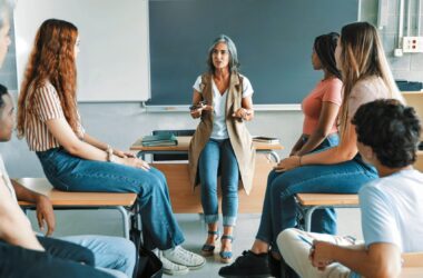 un grupo de alumnos y alumnas en un aula en torno a una profesora