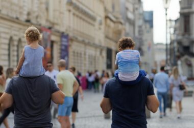 Dos padres caminan con sus hijos pequeños en hombros