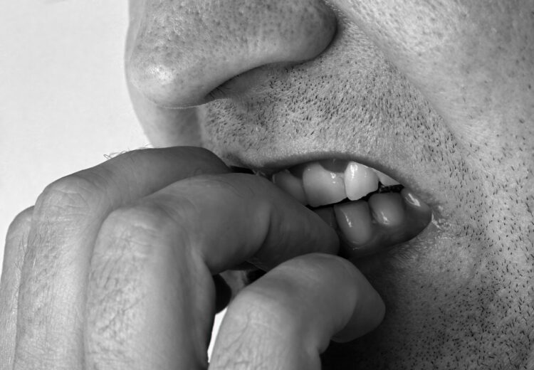 imagen detalle que muestra a un hombre mordiéndose las uñas