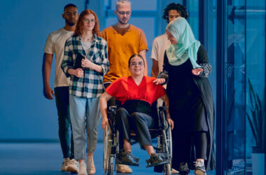 jóvenes estudiantes caminan por un pasillo, una de ellas va en silla de ruedas