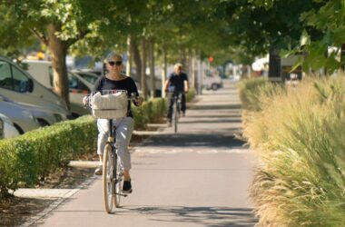 Dos ciclistas, una mujer en primer plano. circulan por un carril para bicicletas en un entorno urbano