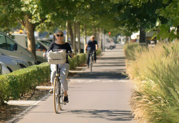 Dos ciclistas, una mujer en primer plano. circulan por un carril para bicicletas en un entorno urbano