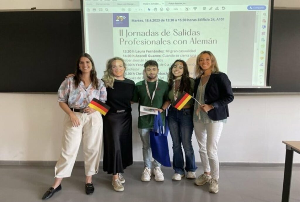 Las profesoras Dra. Alice Stender y Dra. Christiane Limbach. posan junto al alumnado y un cartel de las jornadas de fondo.