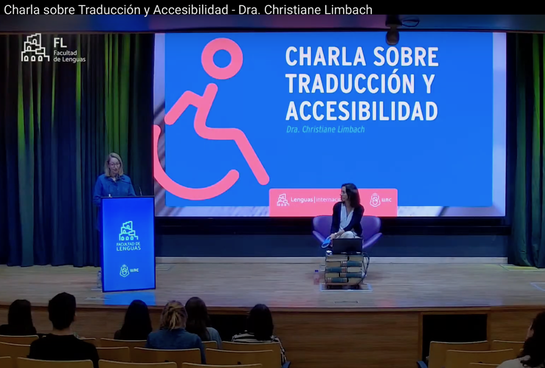 La doctora Limbach impartiendo la charla en el auditorio. Ella en el centro y una gran pantalla con el cartel al fondo.