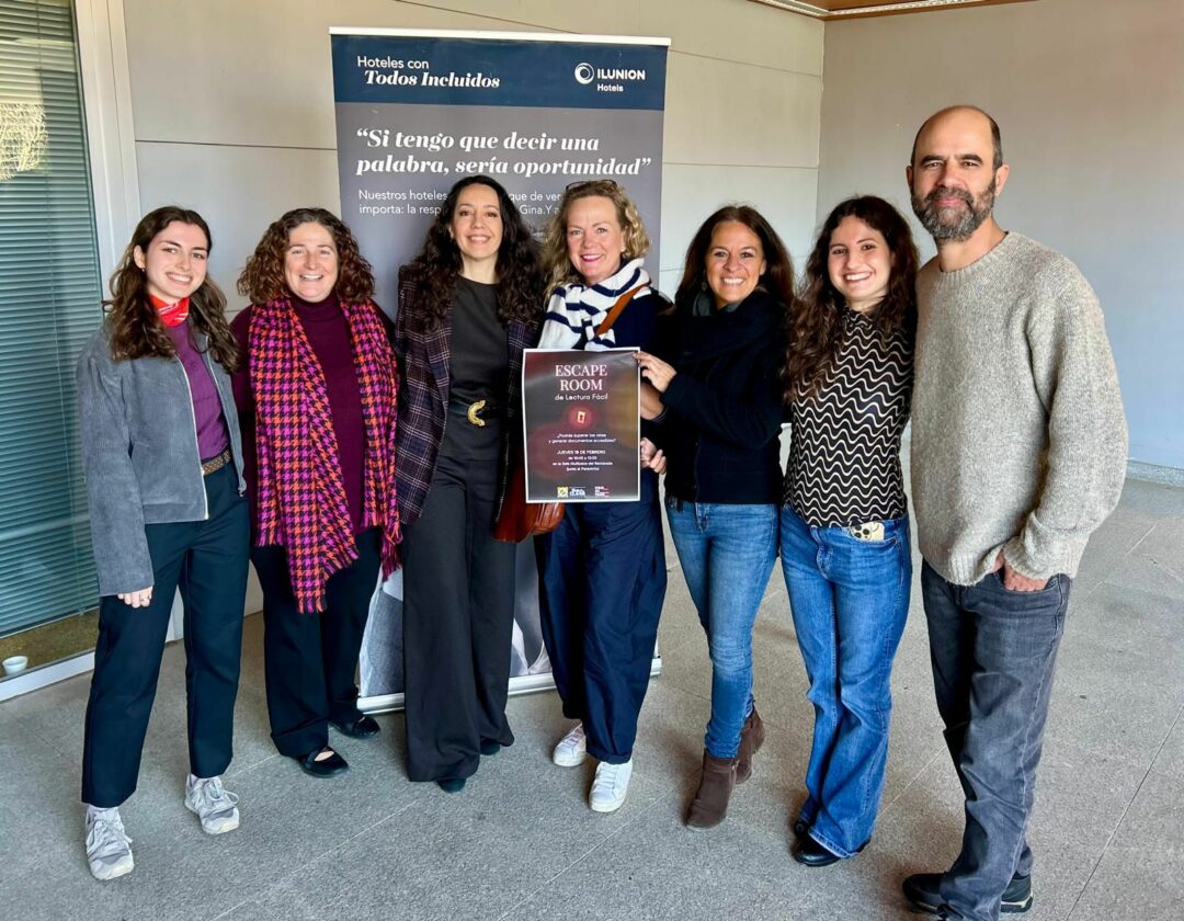 Foto de grupo de COMINTRAD con el cartel del Escape Room de Lectura Fácil. De derecha a izquierda, Sergio España, Desirée Avilés, Carmen Álvarez, Alice Stender, Ana Medina, Patricia Balaguer y Carmen Moreno,