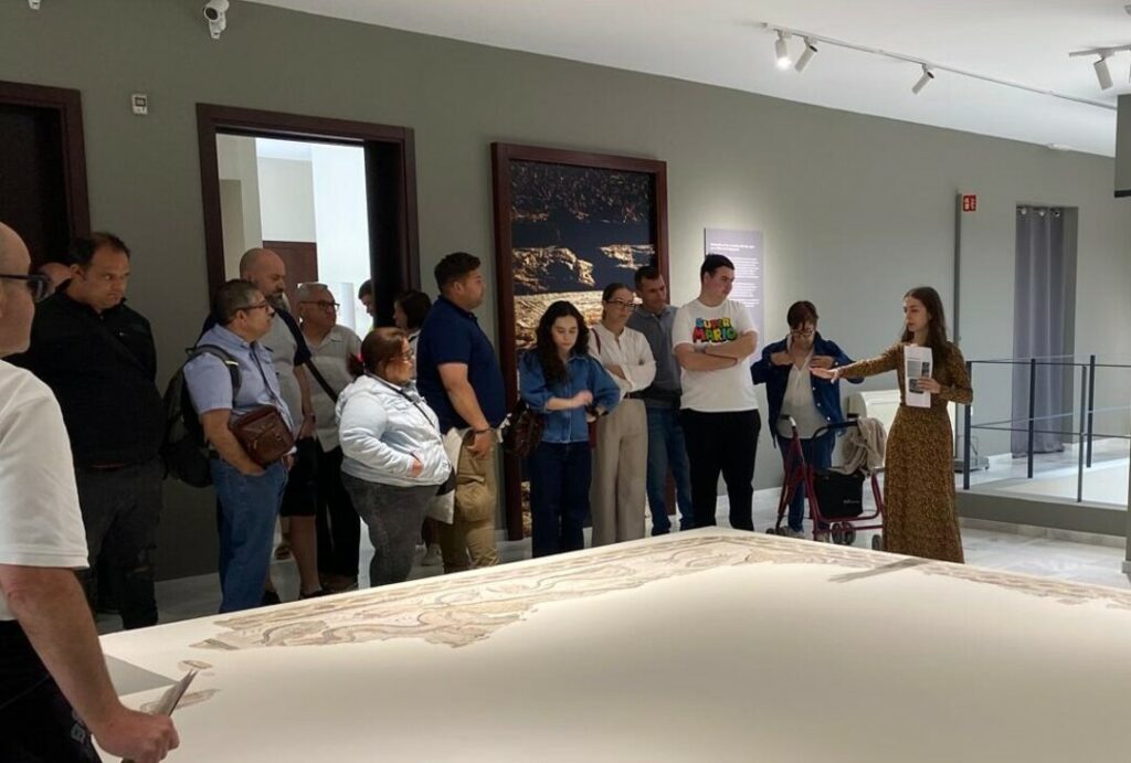 La imagen muestra a Carmen Moreno explicando la historia de uno de los mosaicos del museo a los visitantes
